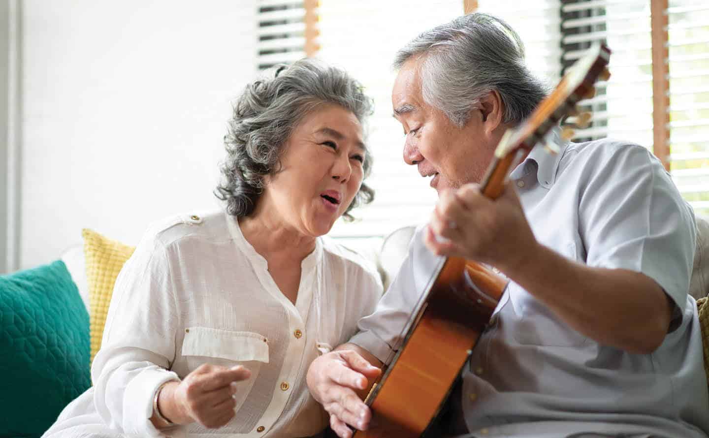 elderly couple singing and playing guitar