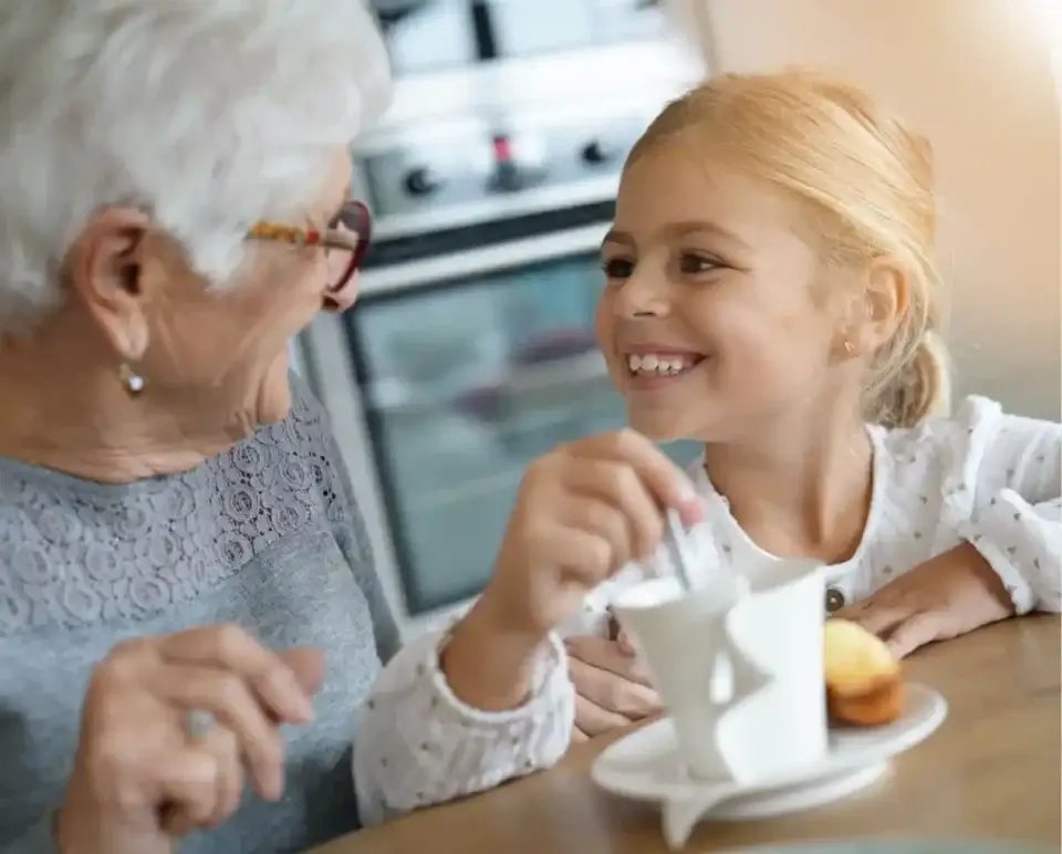 grandma and granddaughter at table sharing a hot drink